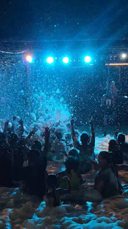 Foam party at night under bright blue spotlights